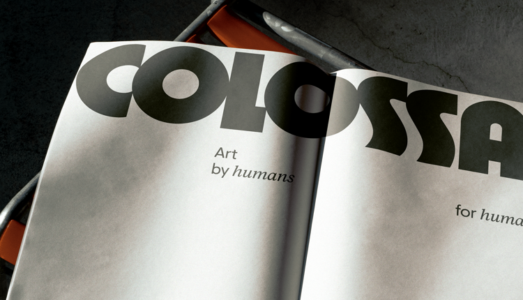 Colossal, art by humans for humans, printed on newsprint resting on a bench